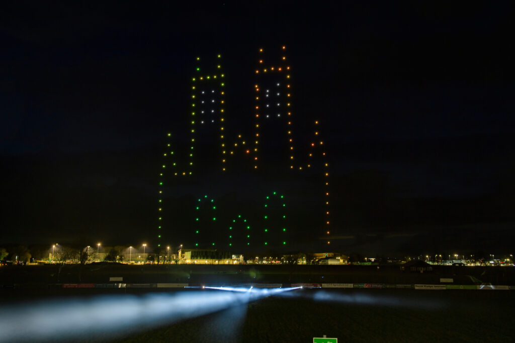 A nighttime scene features a light display of two towering structures created by colorful, illuminated dots. Spotlights shine upwards, enhancing the dark sky and a distant view of dimly lit buildings below. It's a breathtaking sight reminiscent of the elegance showcased at the 2025 Lincolnshire Business Awards.